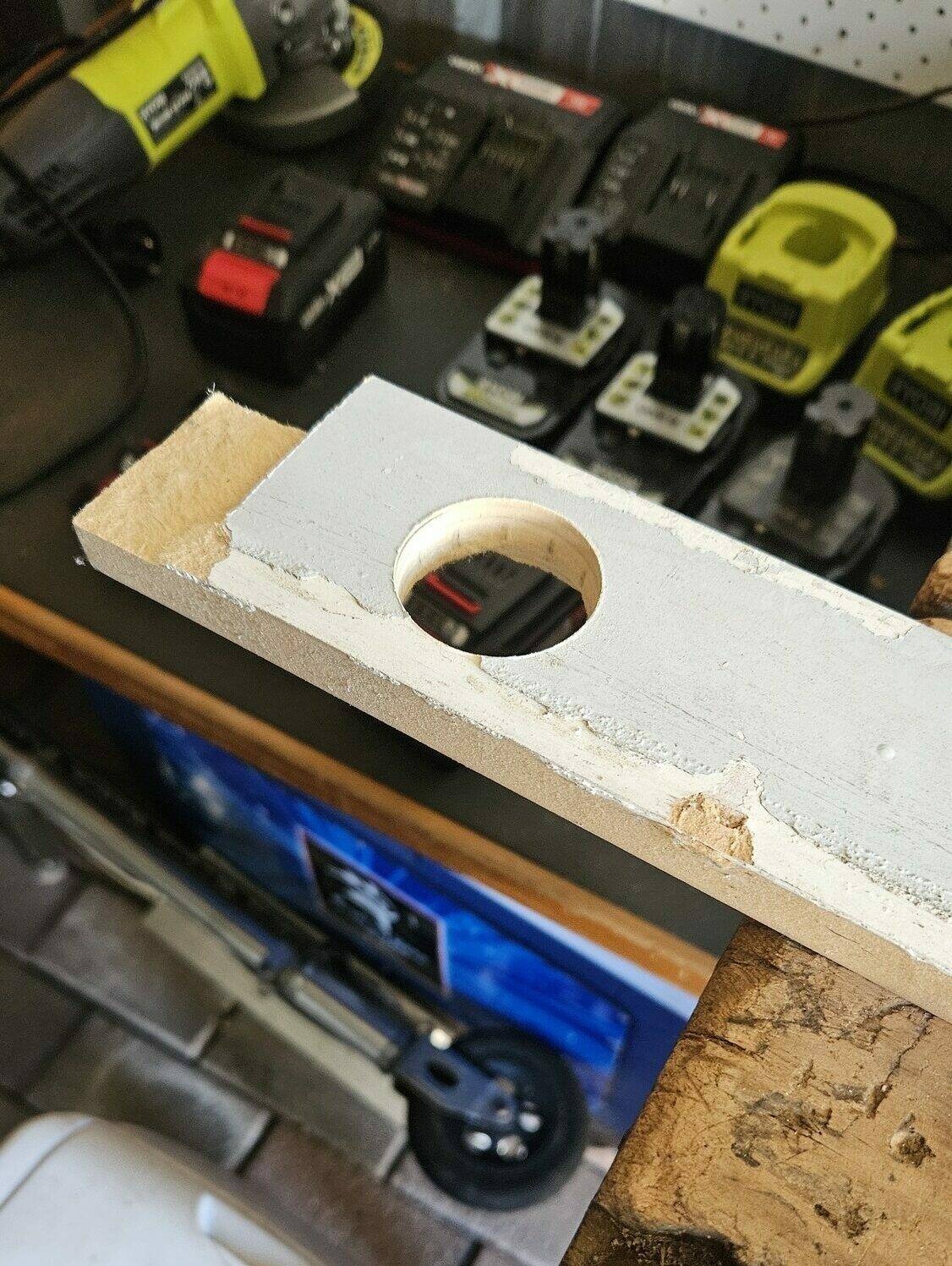 A scrap piece of wood with a hole drilled out of it.
