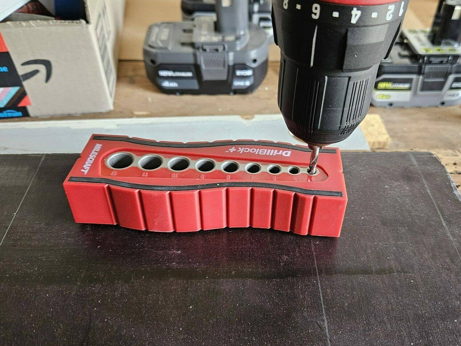 Drilling a hole into a piece of wood, using a Drillblock tool to keep the drill bit straight.