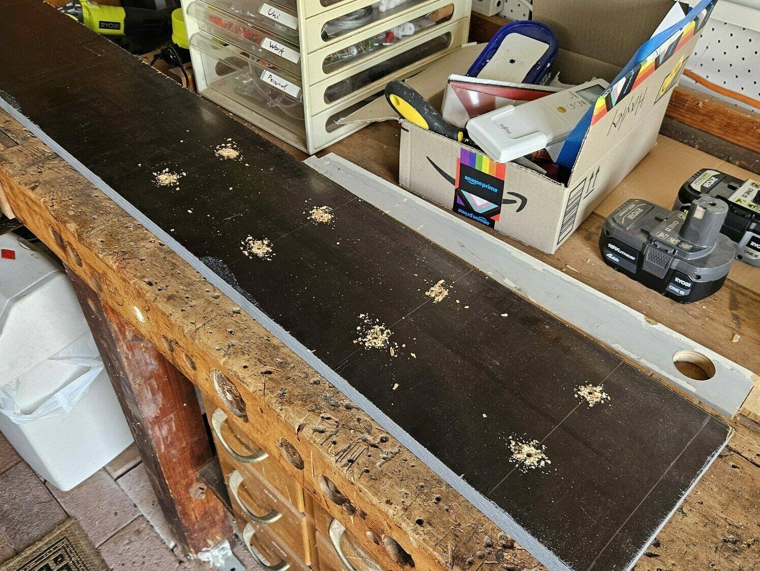 The wooden board with a grid of holes drilled in an even 2 by 4 grid.