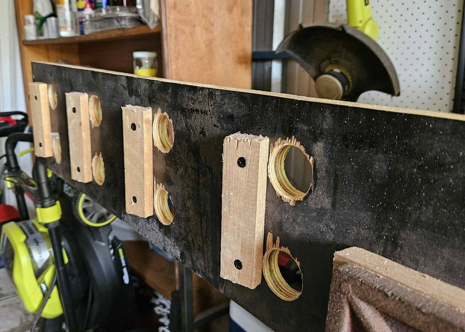 The wooden board with short pieves of scrap wood attached on the rear, just next to each row of 2 holes.