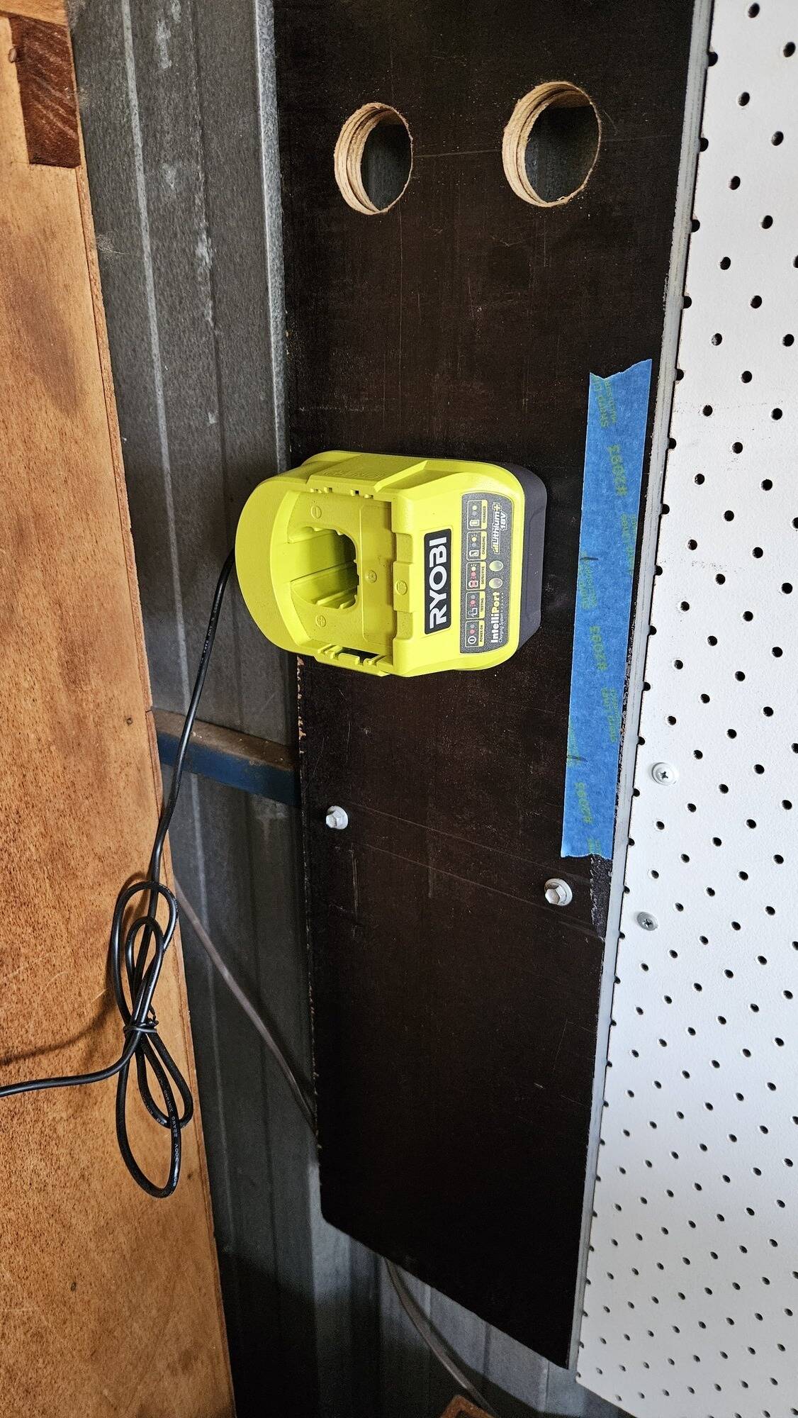 A battery charger mounted to the wooden board.